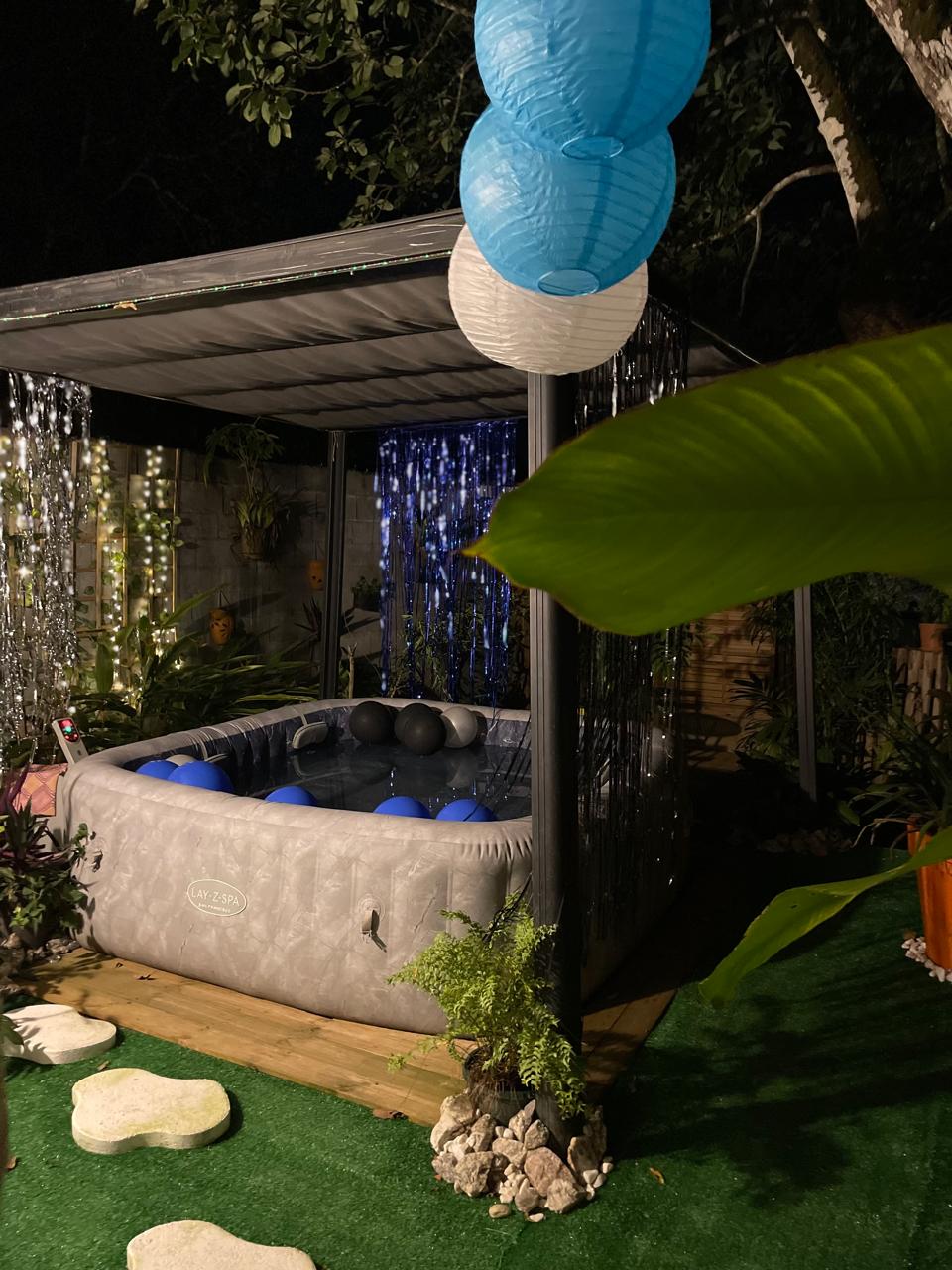 Jacuzzi de nuit avec lampions bleus et rideau scintillant — ambiance d'événement privé