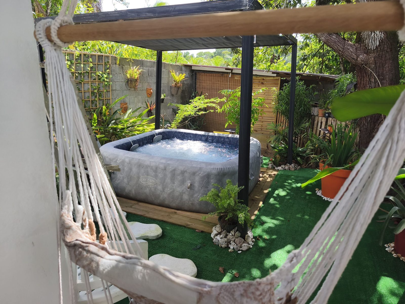 Jacuzzi sous pergola avec hamac, vu du jardin tropical
